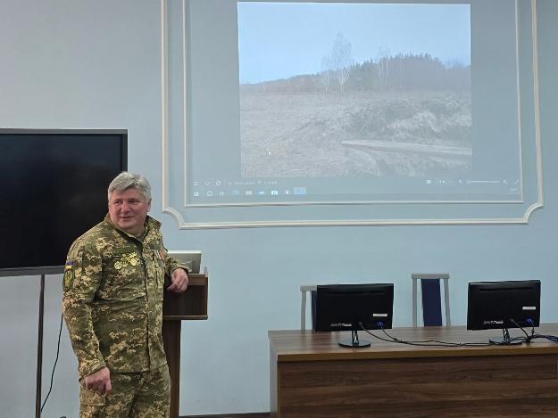 A person in military uniform standing in front of a screenAI-generated content may be incorrect.