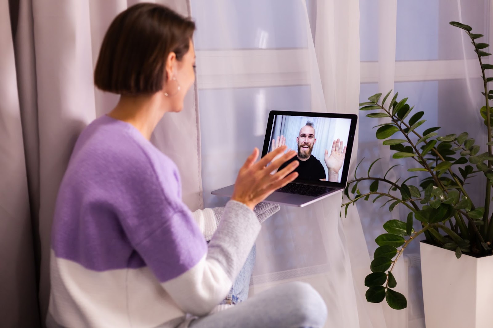 Virtual therapy session with a woman in her living room with a man on a computer screen. 