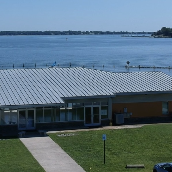 Aerial view of a pre-engineered steel community center by the water with a modern design focused on natural light.