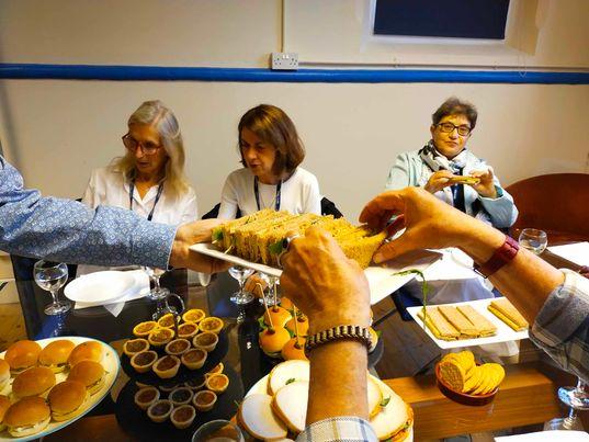 A group of people sitting around a table with food

Description automatically generated