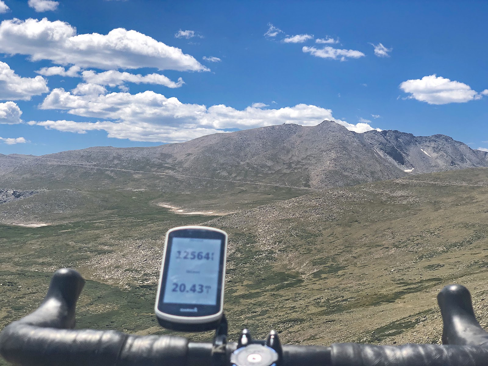 Cycling Mt. Evans, Colorado - view of bike handlebars and Garmin overlooking mountainside, Garmin reads 12,564 feet