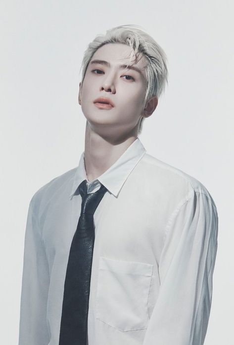 This contains a picture of Jaehyun in a white shirt and black tie posing for a photo with his head tilted to the side