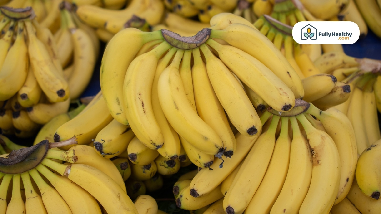 Multiple banana bunches stacked at a market stall