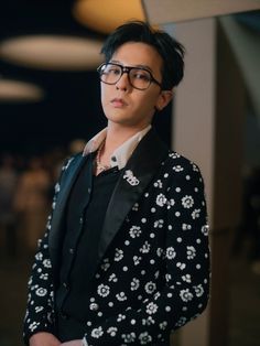 This contains an image of G-Dragon wearing glasses and a floral jacket