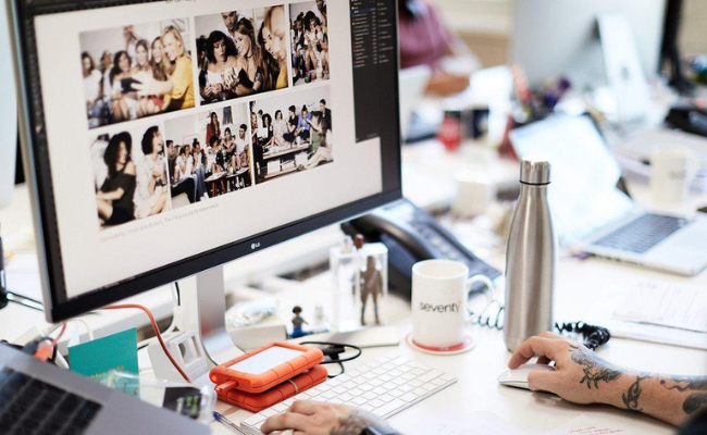 Person in an office using Photoshop on a desktop.