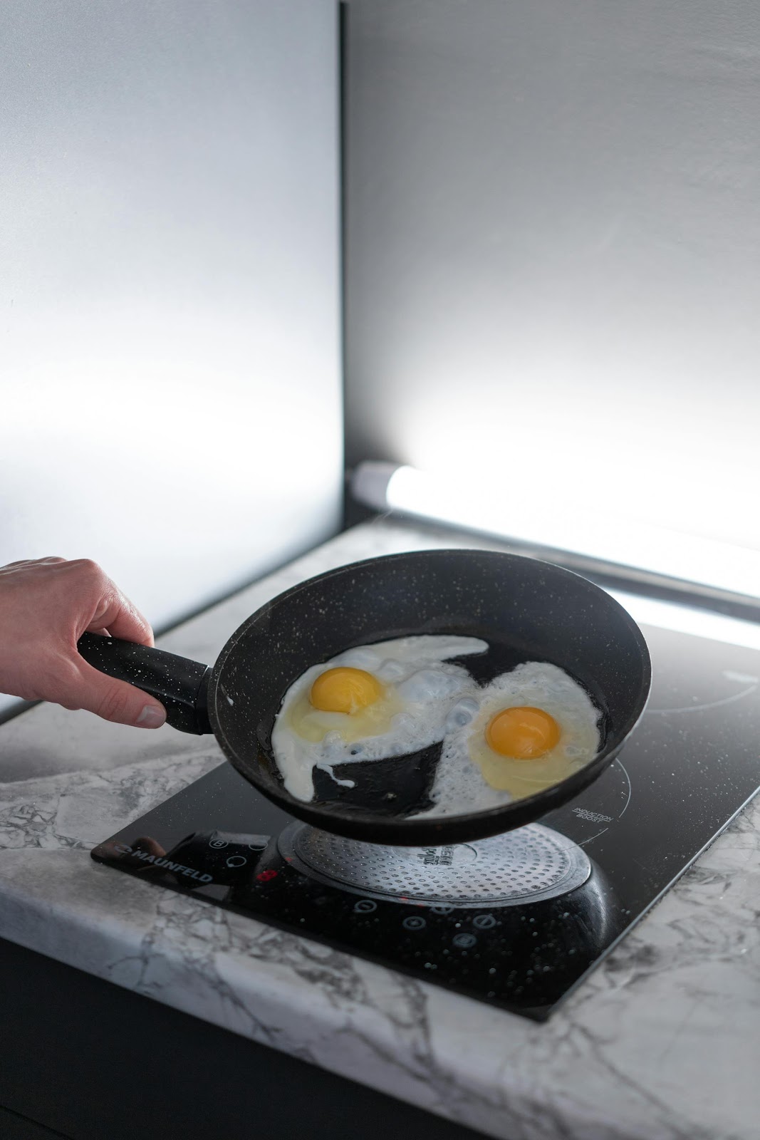 A closeup shot of a person holding a pan with cooked eggs | Source: Pexels