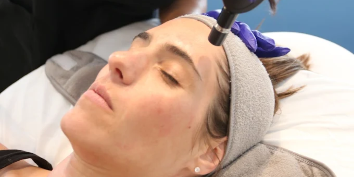 A woman receiving a facial treatment with a hair dryer, highlighting a skincare process for rejuvenation.