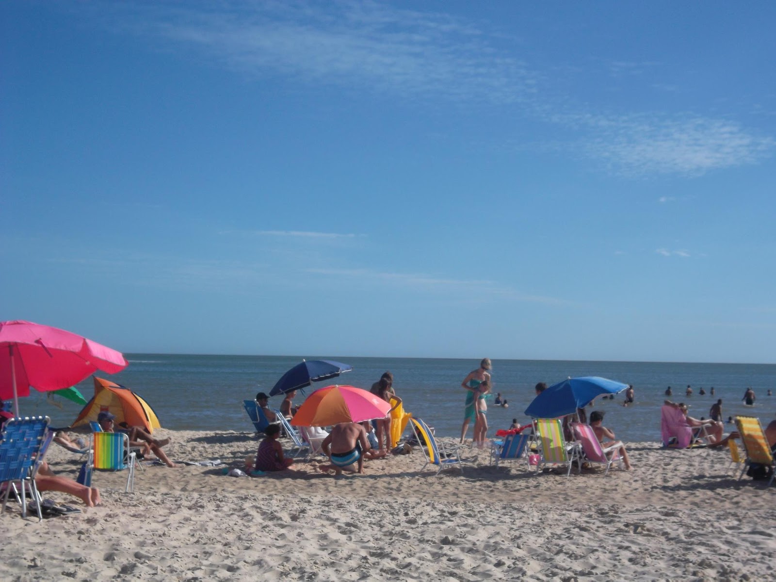 Beach at Playa Hermosa with people relaxing and a colorful umbrella providing shade.