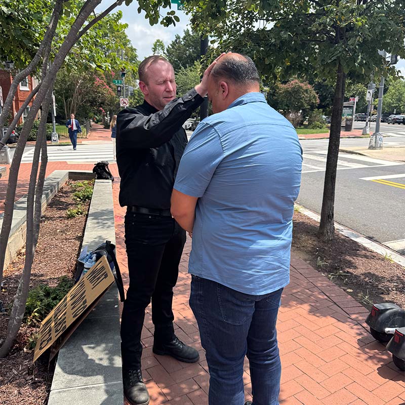 Two pastors pray on the sidewalk in Washington, D.C.