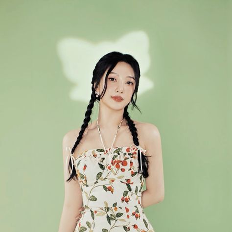 This contain Red Velvet’s Joy with braids standing in front of a green wall wearing a floral dress