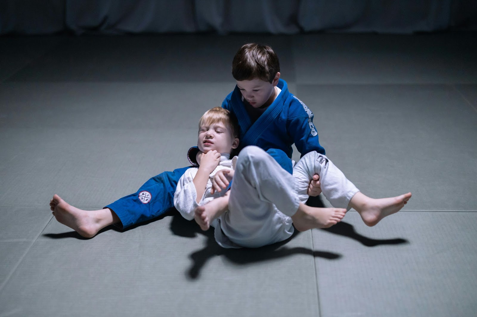 Two young martial arts students practicing ground techniques.