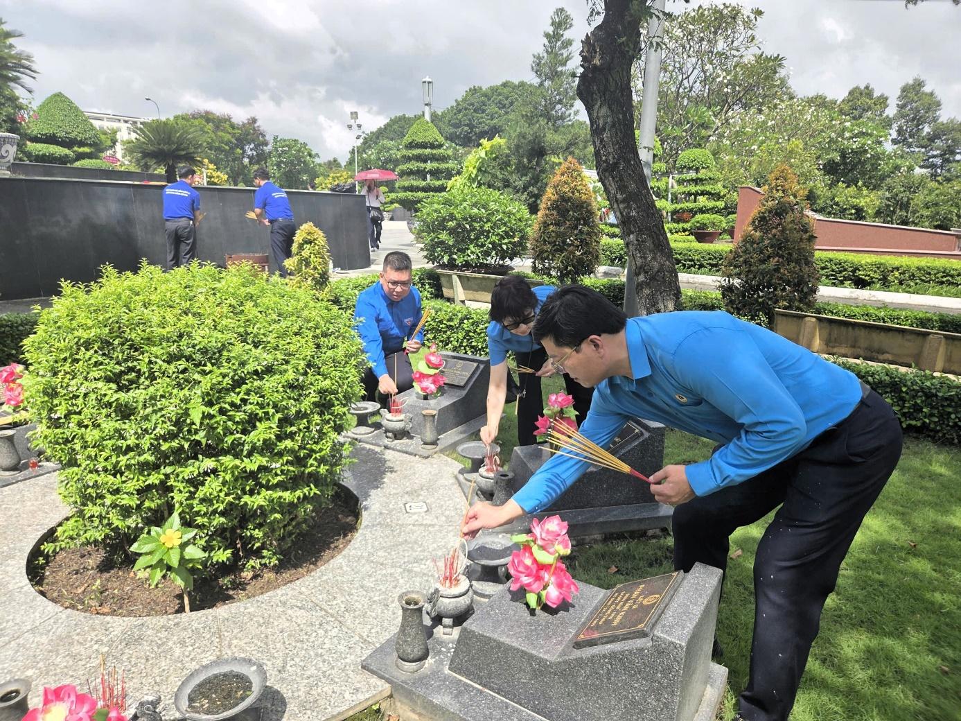 A group of people in blue shirts placing flowers on a graveAI-generated content may be incorrect.