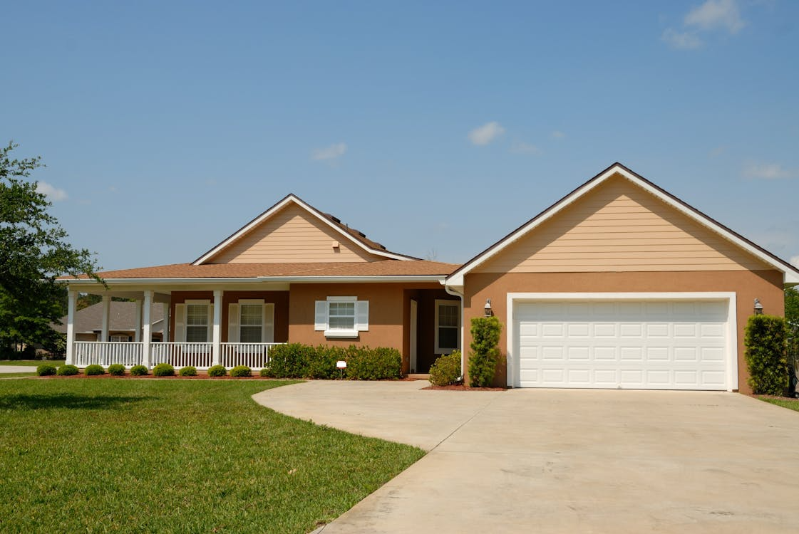 Single-story light orange house with white trim, featuring a clean, well-maintained driveway and neatly manicured front lawn.