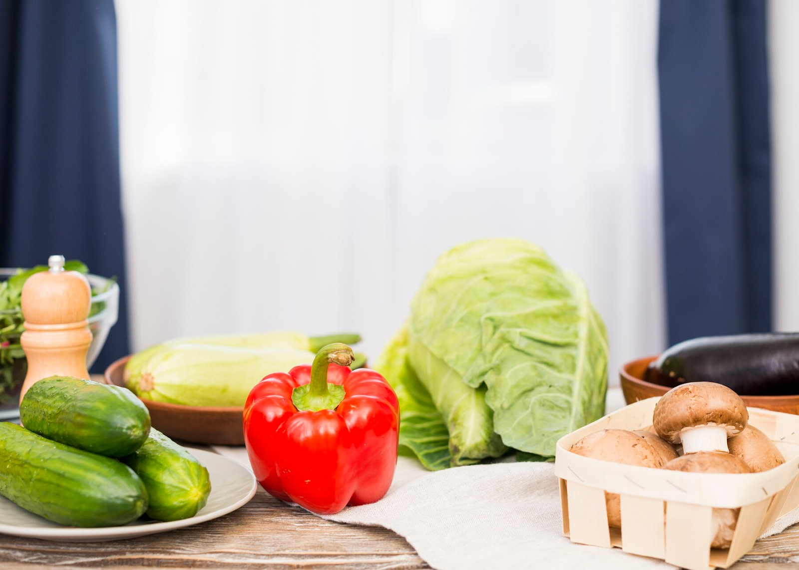 Fresh cucumber, bell pepper, mushroom, and cabbage on a table