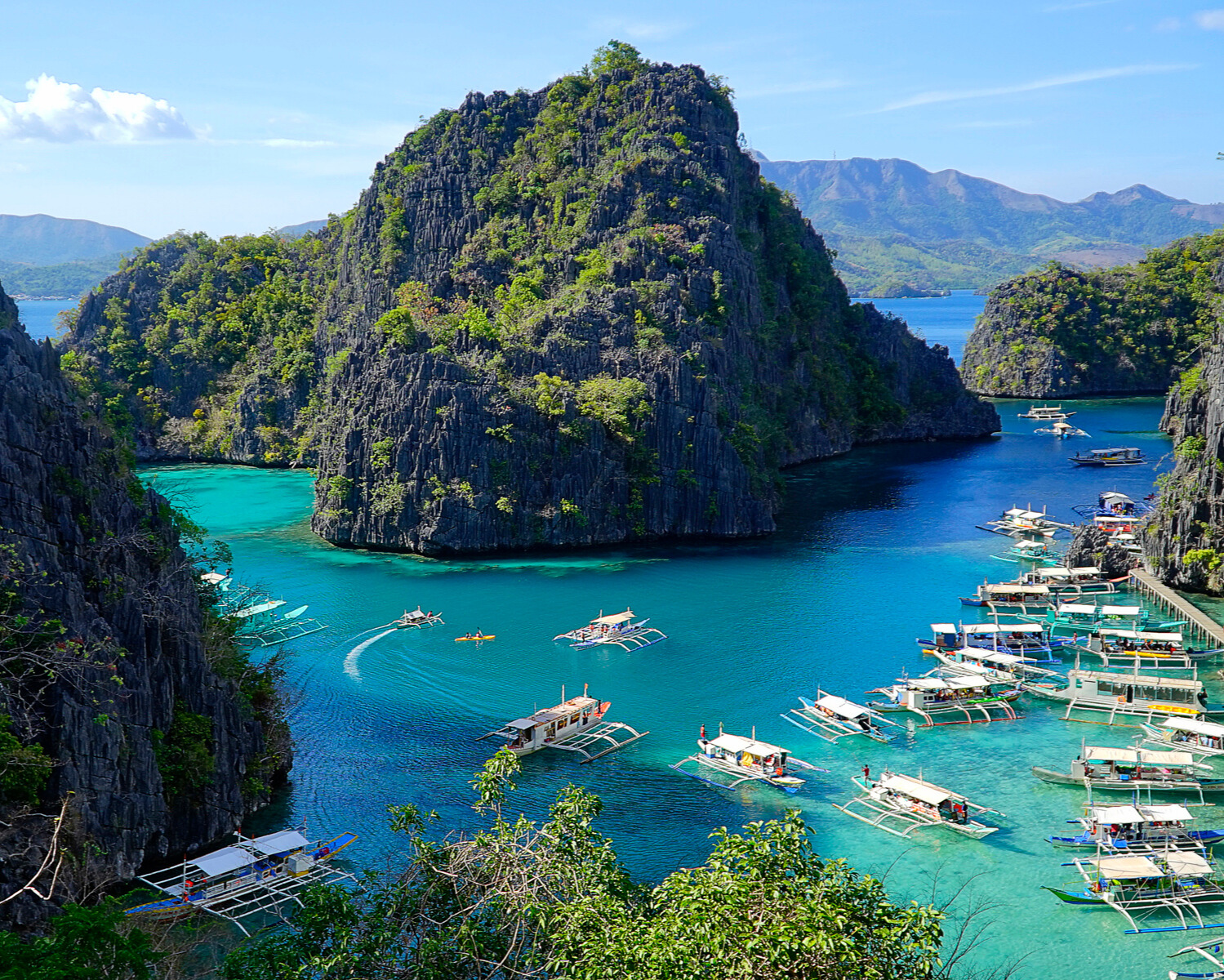 Scenic view of Palawan clear blue water with boats and lush green island