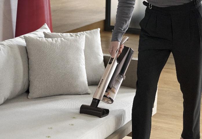 A person vacuuming a couch

Description automatically generated