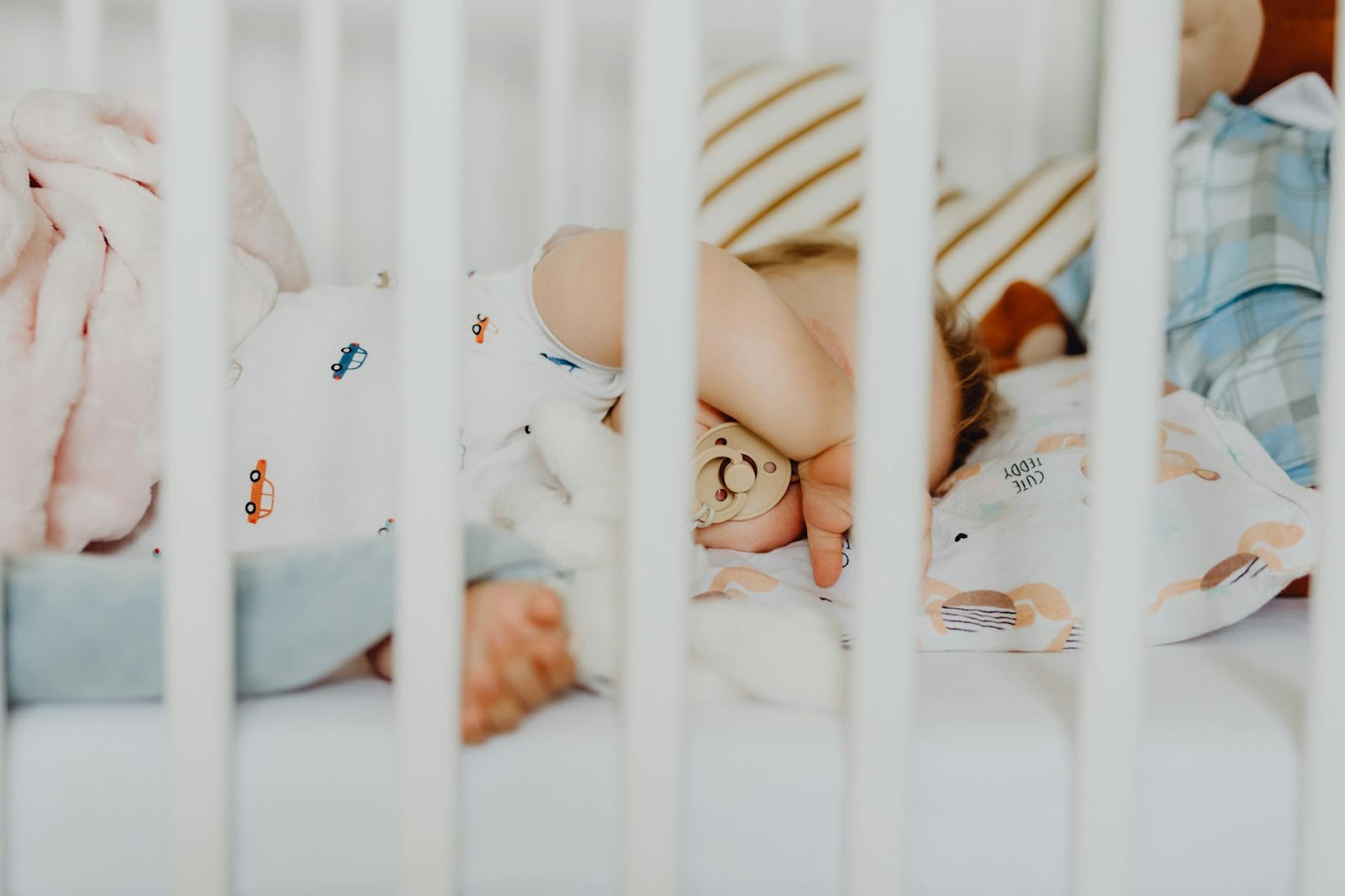 A baby peacefully sleeping with a pacifier in a cozy crib with plush blankets.