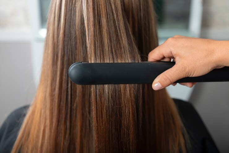 Woman getting her hair straightened at salon
