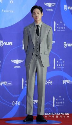 This may contain: a picture of Park Sung Hoon in a suit and tie standing on a red carpet with his hands behind his back