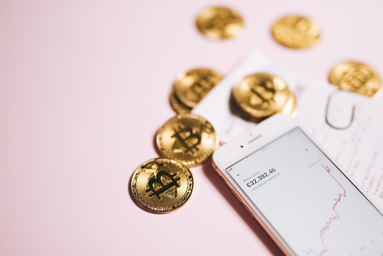 Smartphone displaying cryptocurrency price alongside gold Bitcoin coins