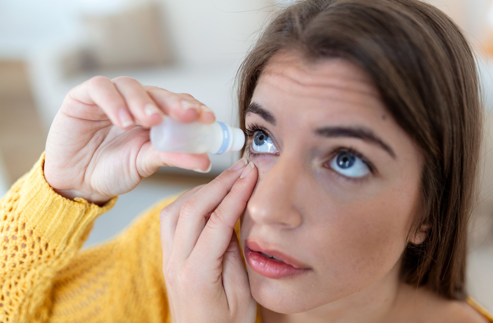 Woman dropping eye lubricant to treat dry eye