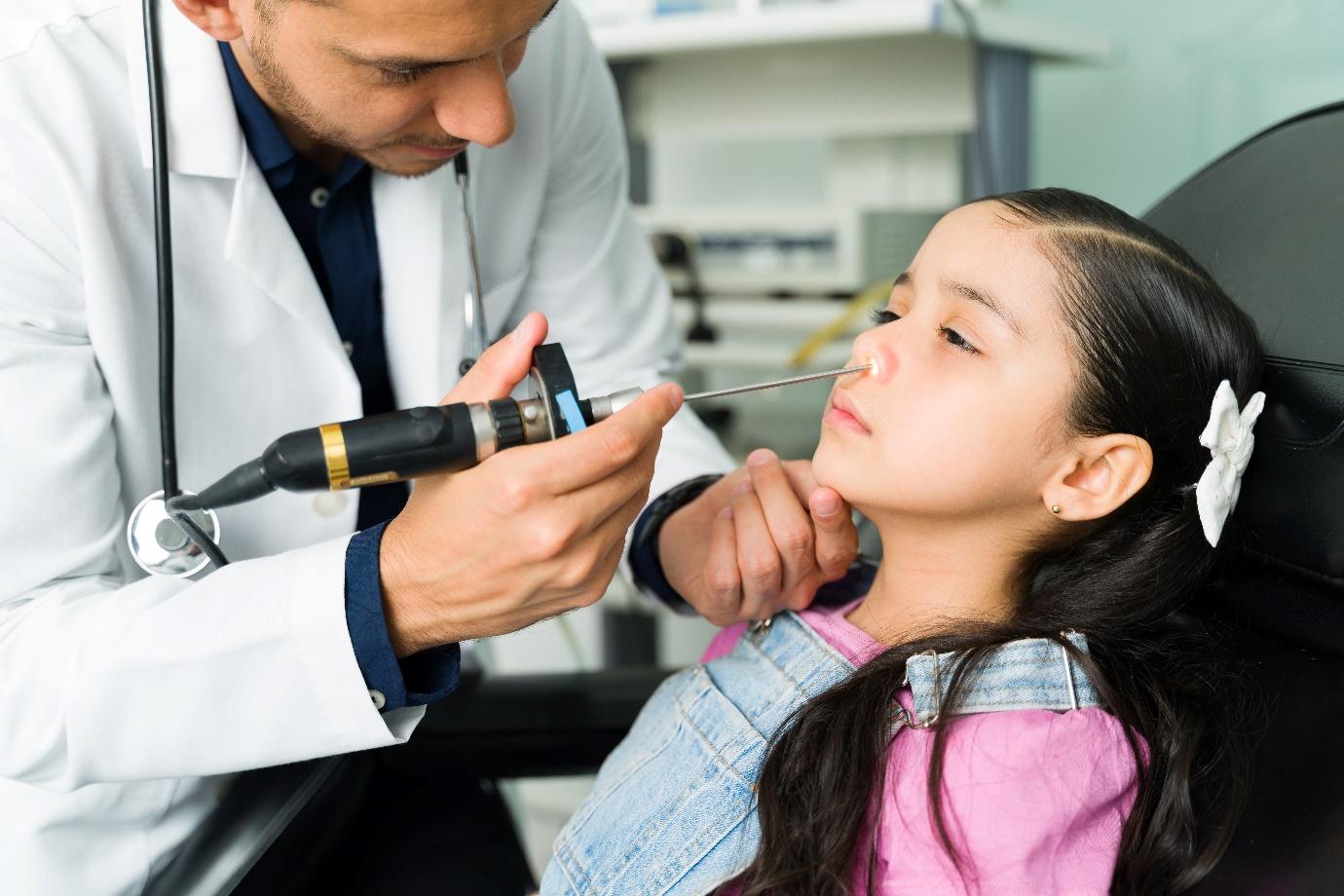 Especialista revisando la nariz de una niña con un endoscopio en un consultorio, durante una evaluación médica.