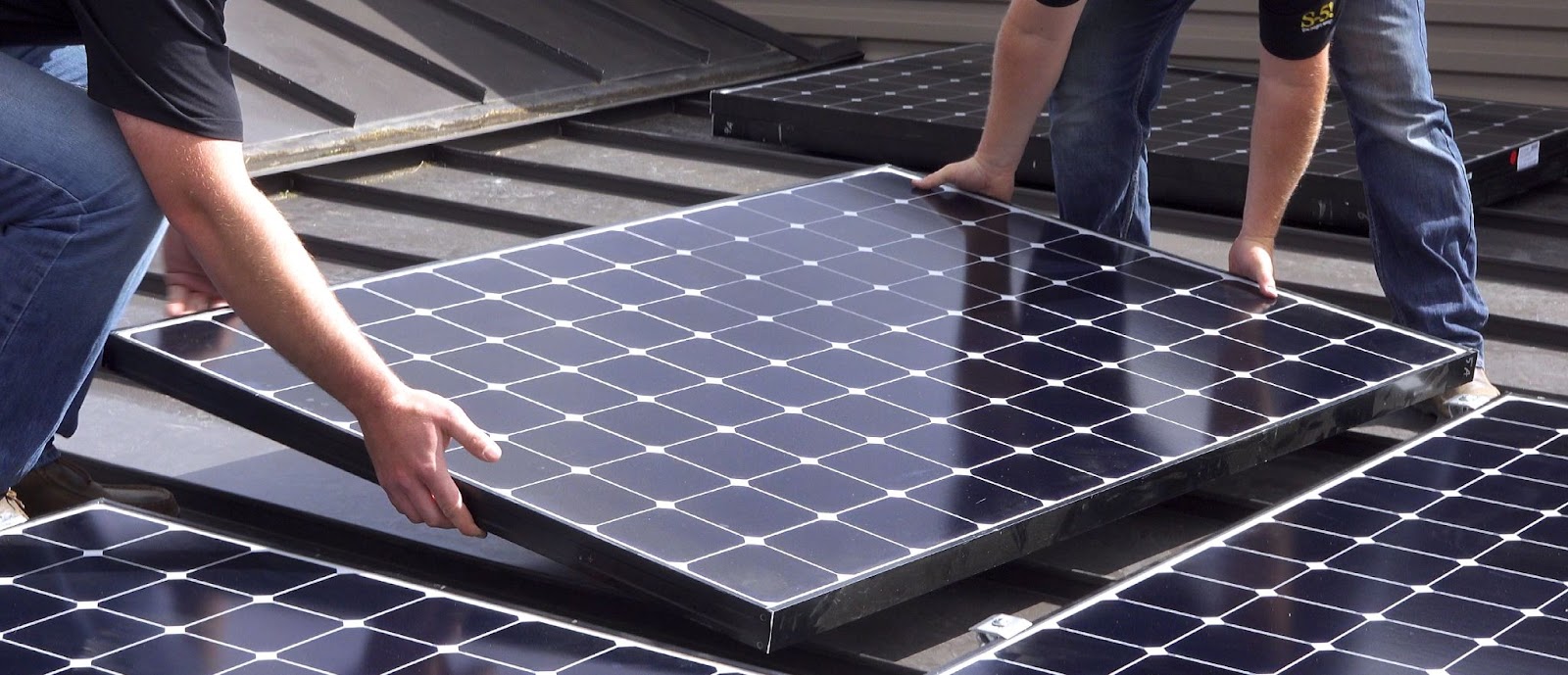 solar installers putting module on metal roof