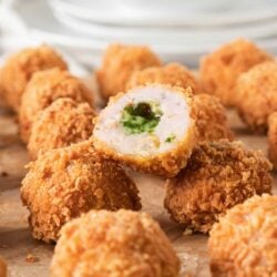 Fried chicken kiev balls on a plate with a bite taken out of one.