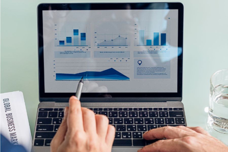 Two individuals analyzing business charts on a laptop screen.