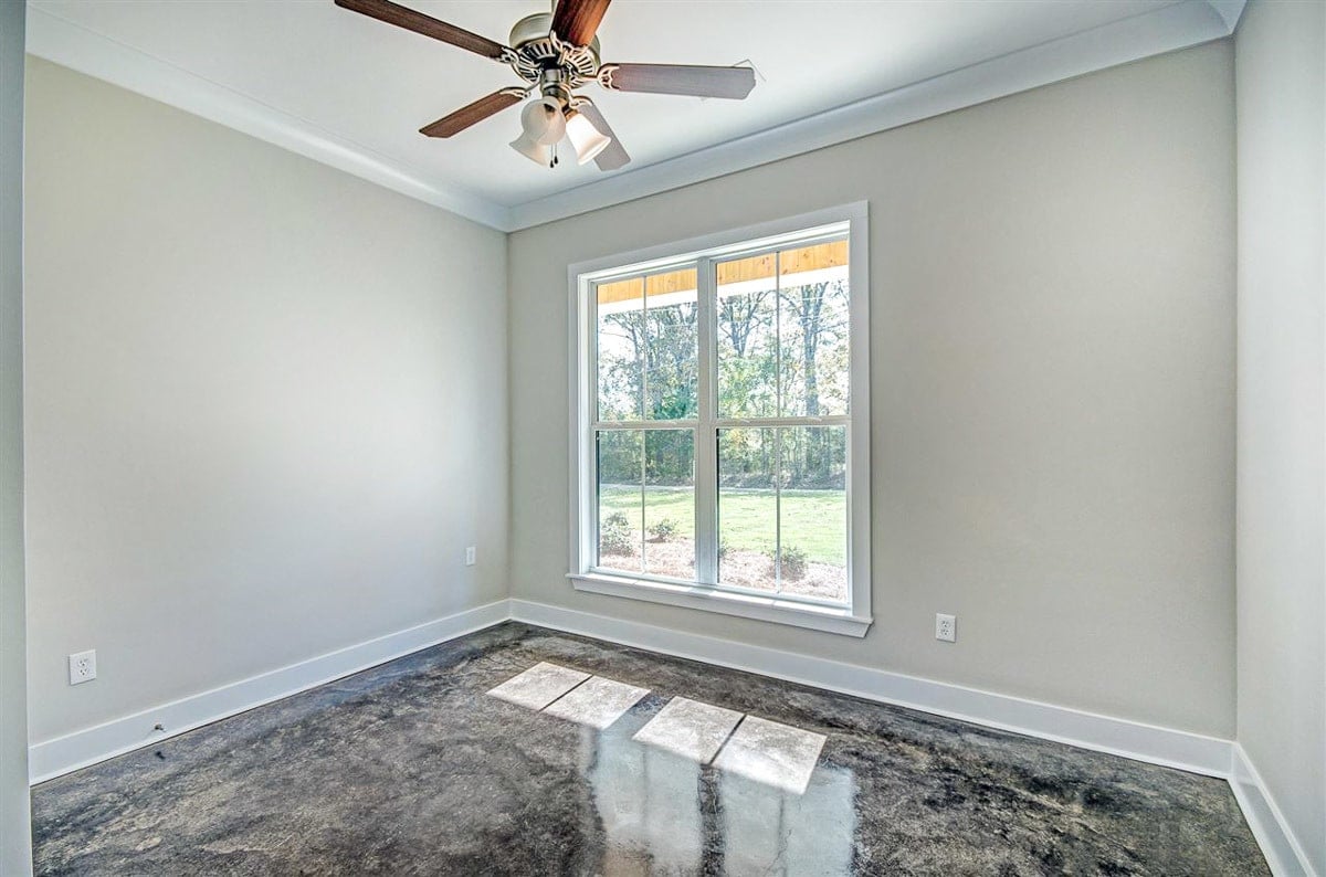 Bedroom with gray walls, a ceiling fan, and a white framed window overlooking the yard.