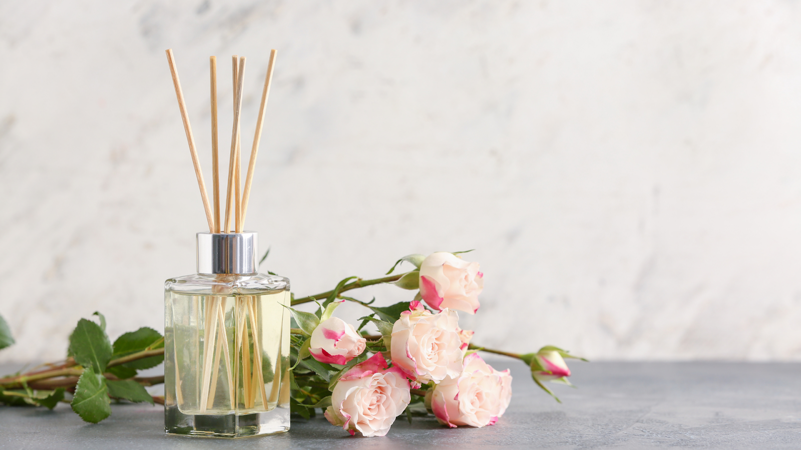 Gambar reed diffuser dengan bunga mawar di sampingnya/Sumber: Canva