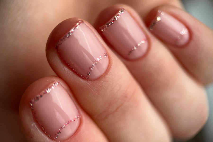 Glitter French tips add sparkle and glamour to a traditional French nail tip design.