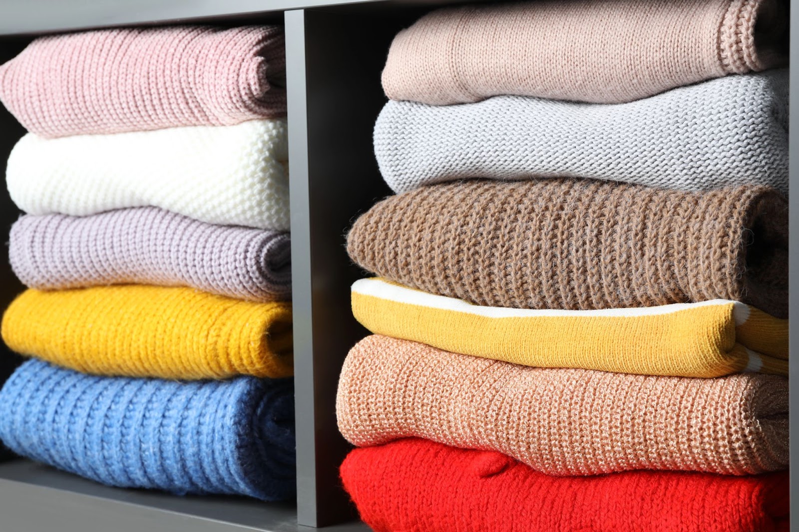 perfectly stacked colorful sweaters on gray shelves