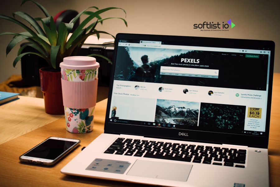 Laptop and smartphone on desk with Pexels website open, coffee cup nearby.