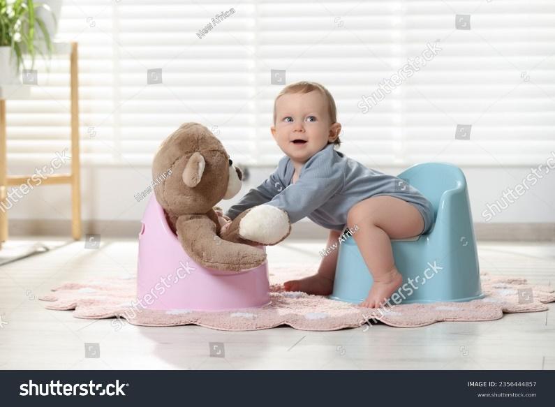 Little child and teddy bear sitting on plastic baby potties indoors