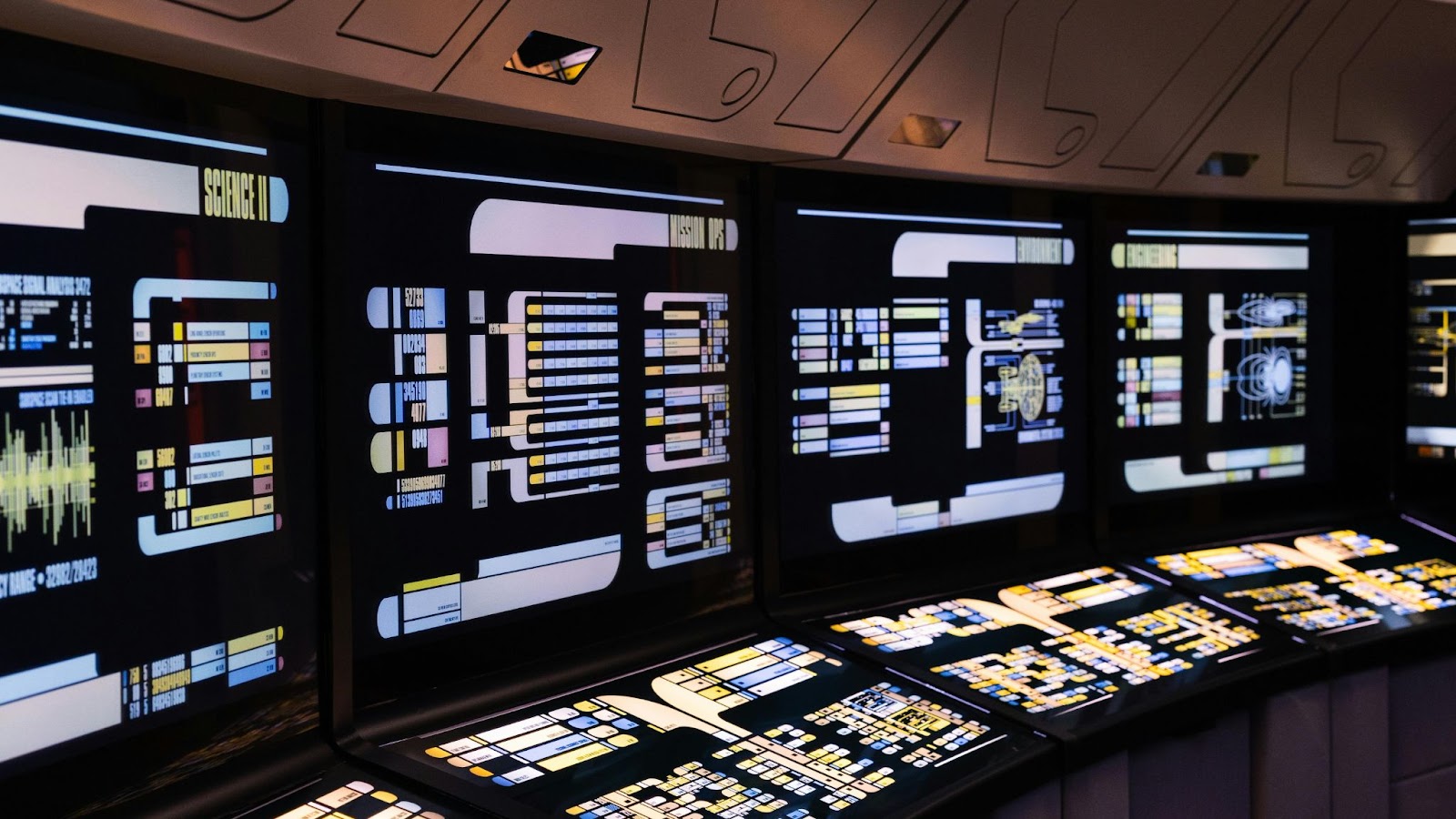 Futuristic command center with multiple digital displays showing real-time cybersecurity threat maps, system alerts, and network monitoring dashboards.
