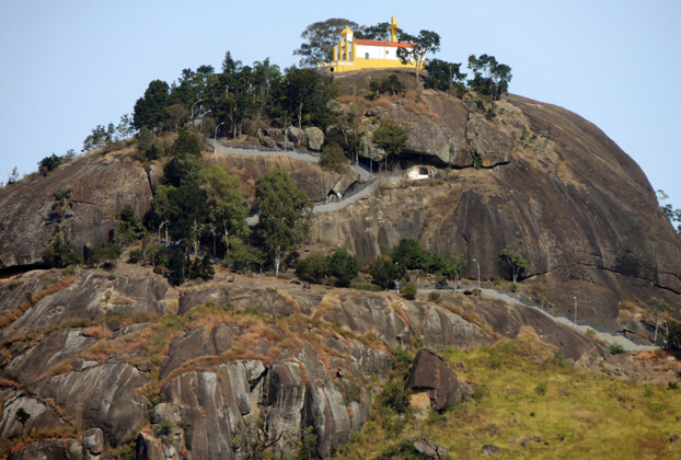 Vista da Pedra bela com a Capela no topo, cercada por árvores e rochas, no Brasil.