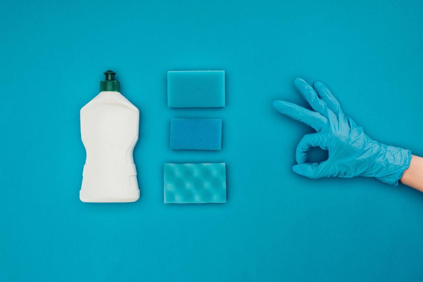 A hand with gloves and a bottle of dish soap

Description automatically generated