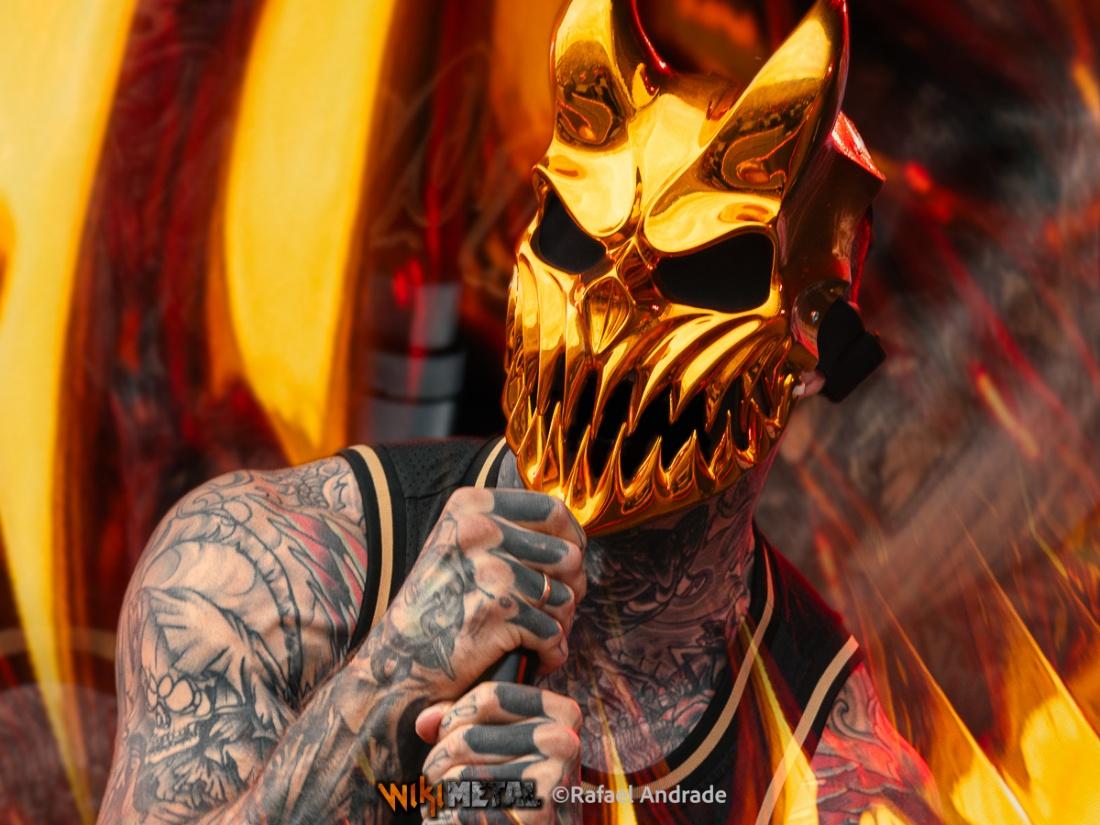 A person with tattoos holding a microphone in front of his face

AI-generated content may be incorrect.