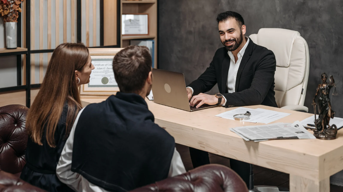 (A friendly attorney consults with two clients in a professional office, creating a warm and trustworthy atmosphere with legal documents and decor.)