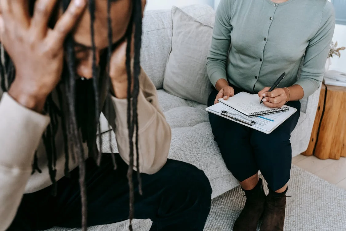 Crop frustrated black man holding head in hands during psychotherapy