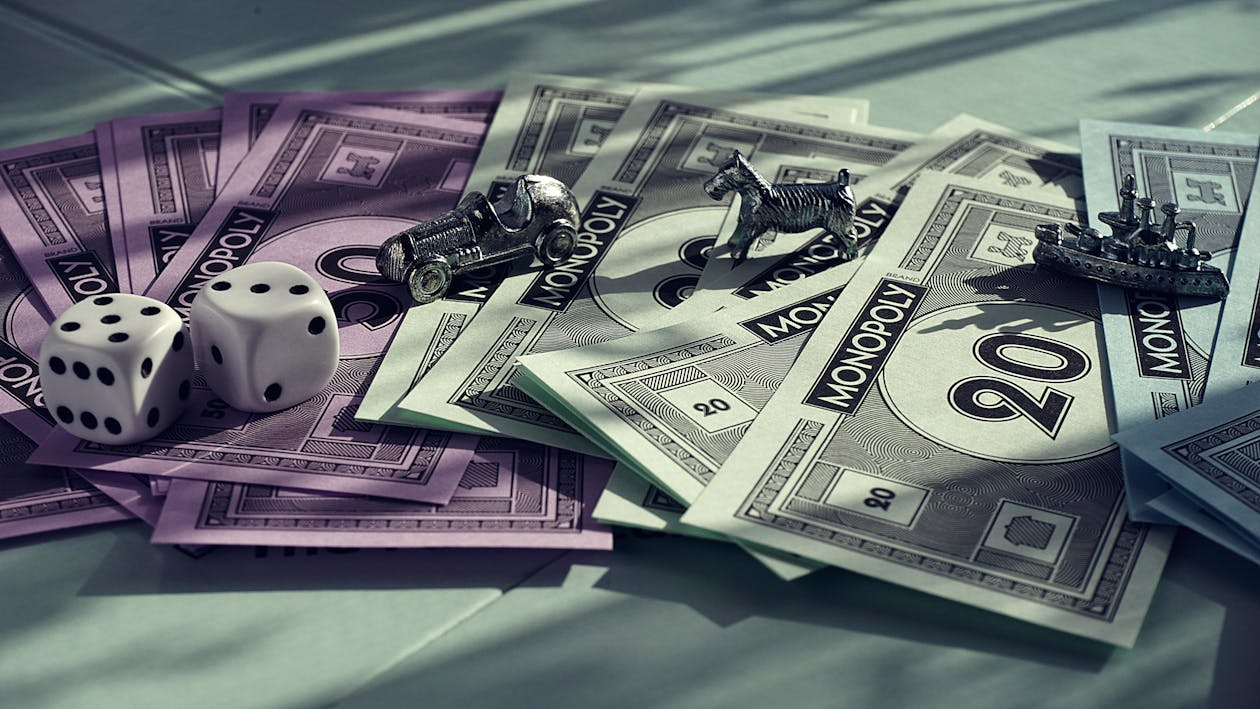 Monopoly money, dog, car, and ship tokens with dice showing numbers 5 and 3 on a Monopoly board – best strategy for financial freedom.