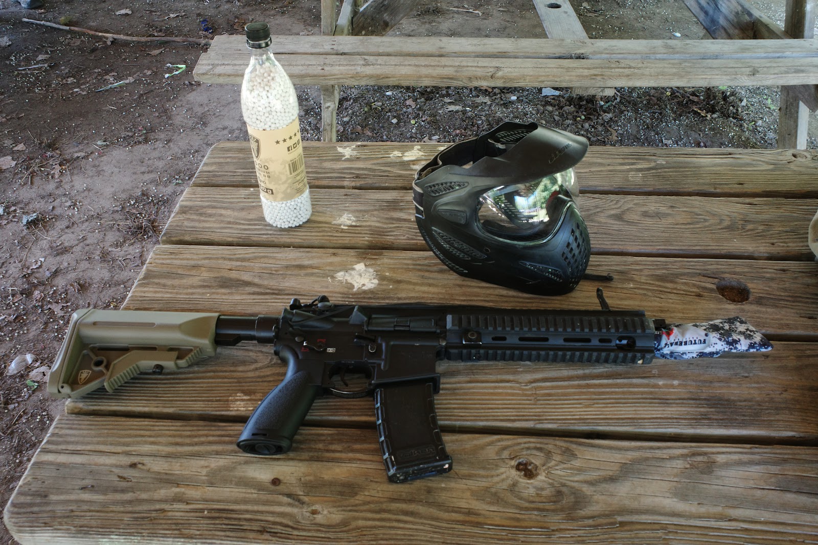 M4-style airsoft rifle, protective mask, and can of BBs.