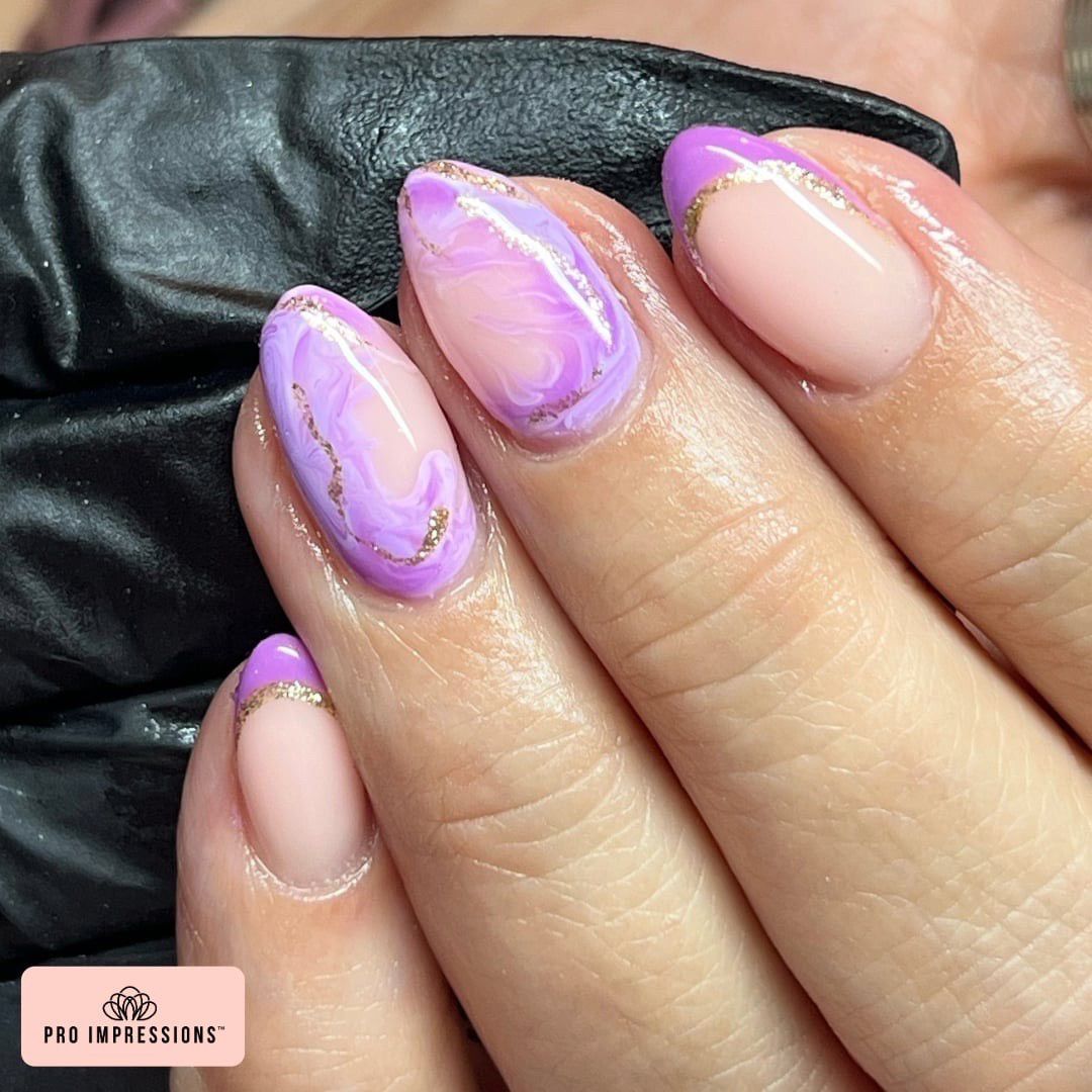 A close-up of a woman's hand showcasing elegant purple and gold nail polish, highlighting her stylish manicure.