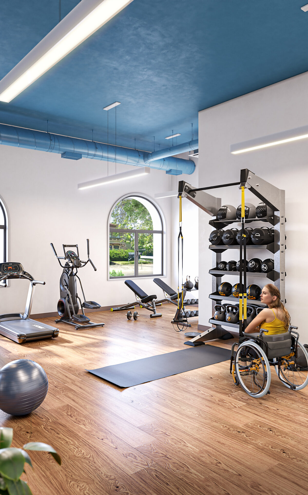 A woman in a wheelchair sits in a gym at a housing community for adults with disabilities