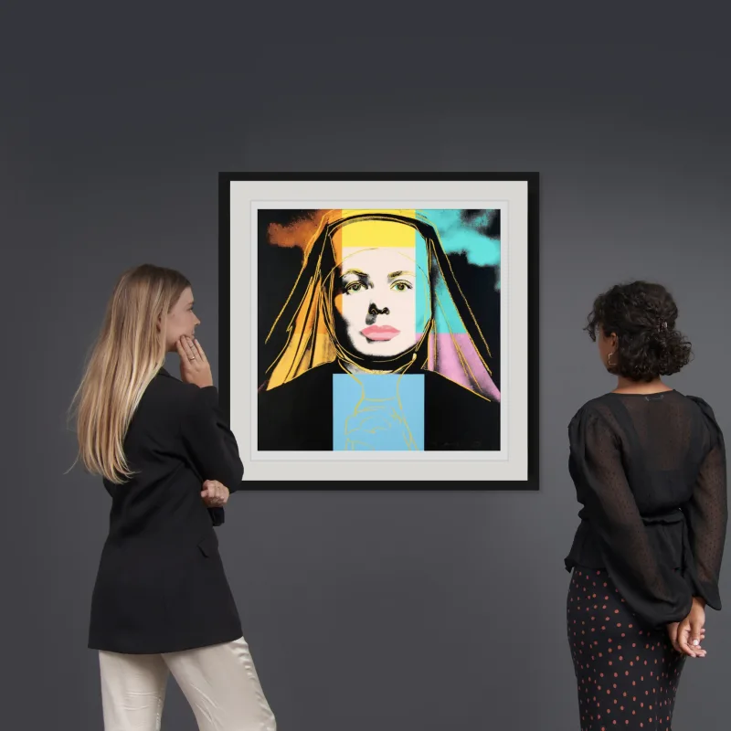 Two collectors view this Andy Warhol, signed print, Ingrid Bergman, The Nun (FS II.314), as it displays in a gallery where Andy Warhol art sold.