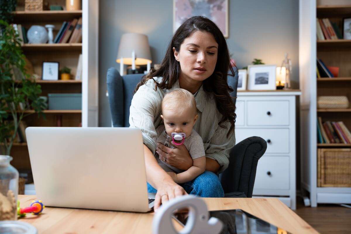 FMLA Hawaii: mother taking care of her baby while using a tablet