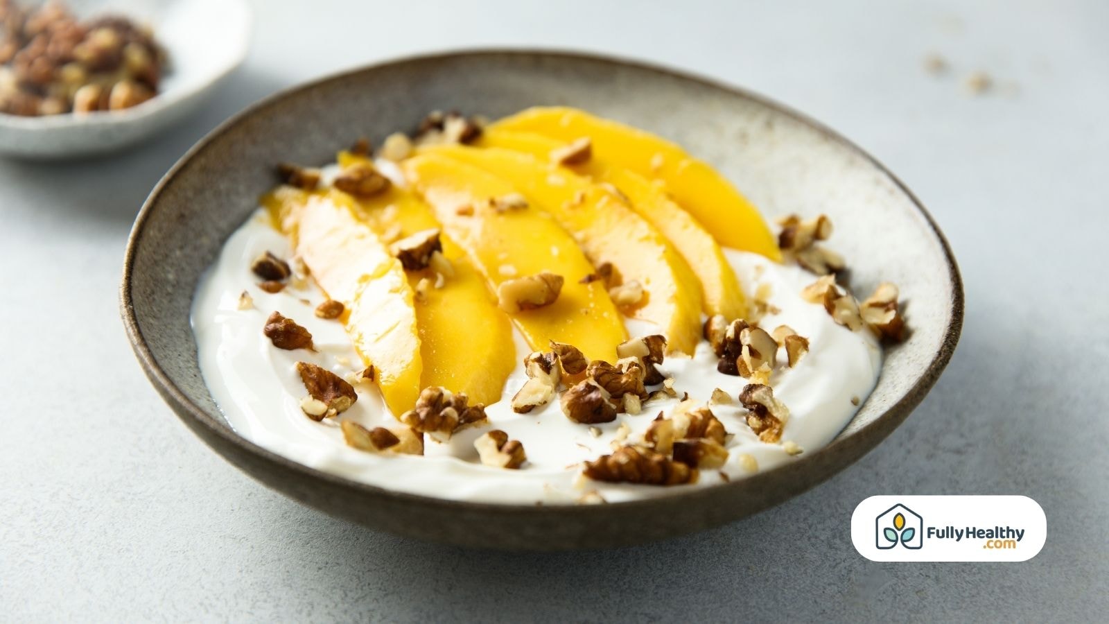 Mango slices on yogurt topped with crunchy chopped nuts