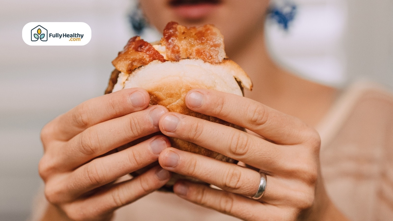 A person holding a bacon sandwich