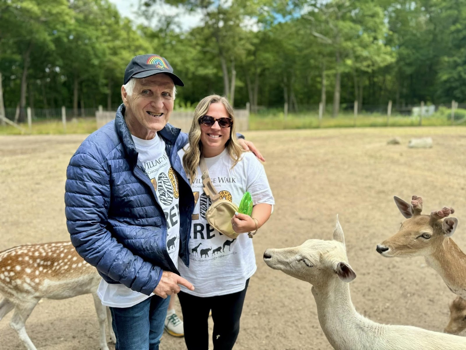 An assisted living resident and staff member smiling with deer in the background